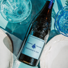 Eine Flasche Pierre Troupel Rotwein AOC Châteaneuf-du-Pape liegt auf dem Tisch mit einem blauen Tischdecke